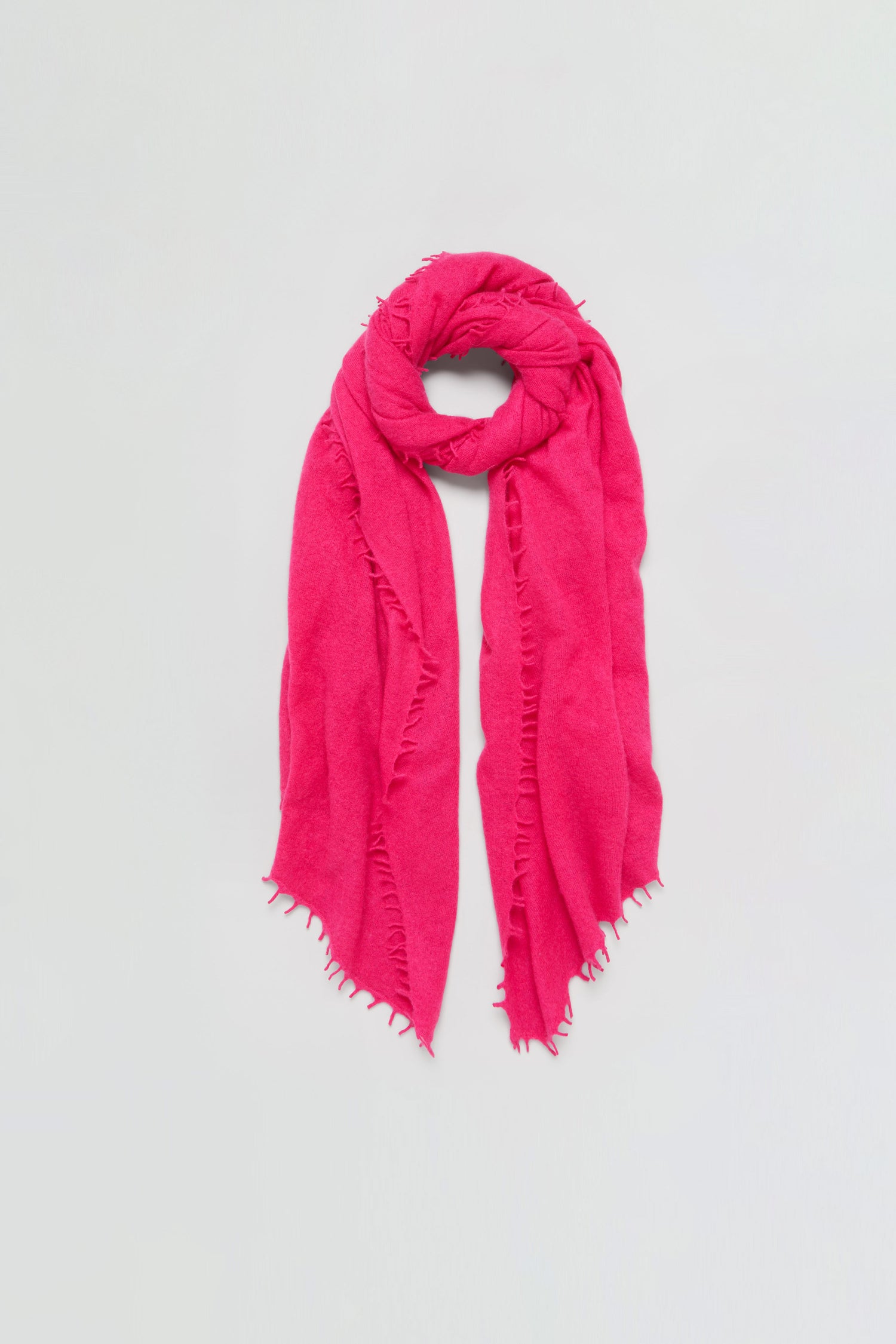 The Fuchsia Soft Cashmere Scarf, featuring frayed edges, is displayed flat against a simple light background.