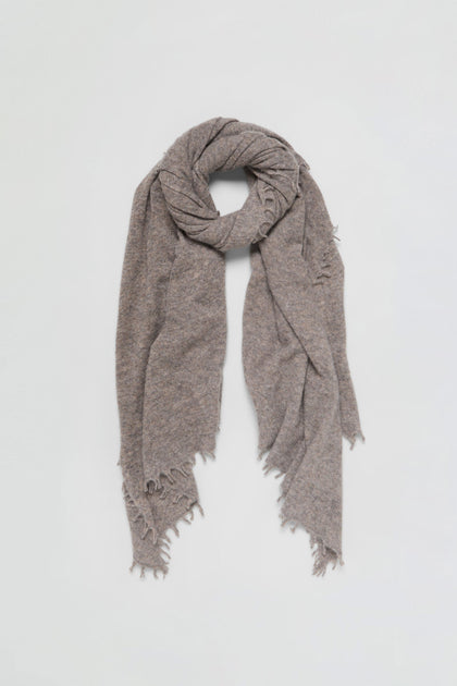 A Sand Soft Cashmere Scarf in light brown with frayed edges, loosely wrapped in a circular shape on a plain white background.