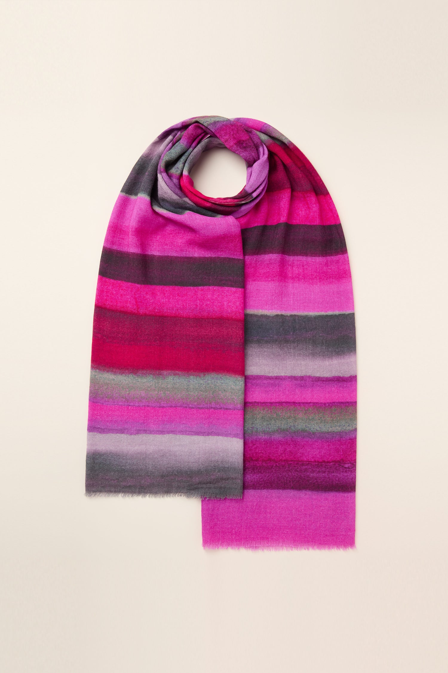 The Crimson Twilight Stripe Scarf is a long and multicolored striped accessory featuring shades of pink, purple, gray, and green set against a plain, light background. This autumn and winter scarf envelops you in cozy sunset hues perfect for chilly days.