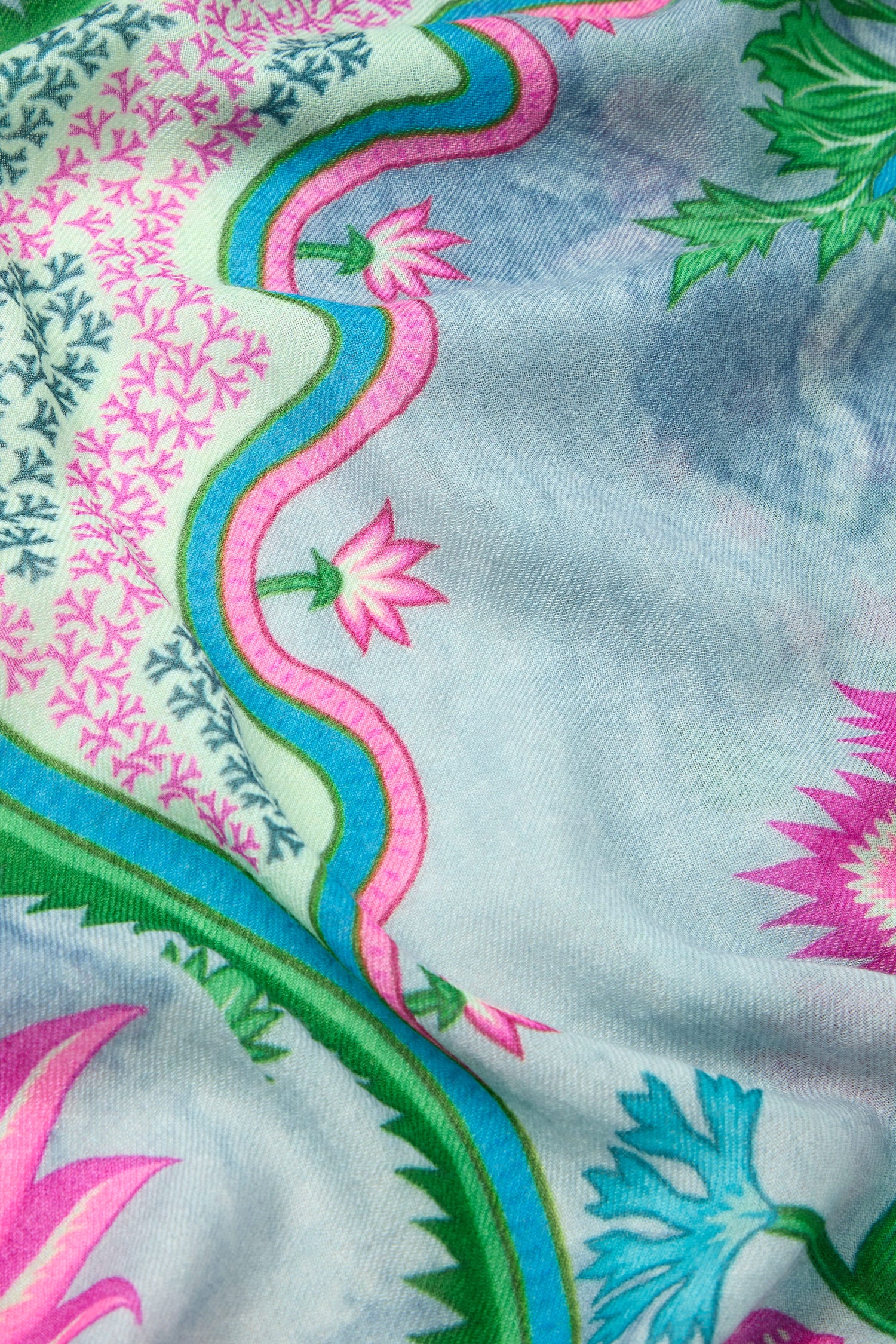 Close-up of the Heavenly Garden Scarf showcasing a floral print with green, pink, and blue flowers on a light blue background crafted from lightweight fabric.