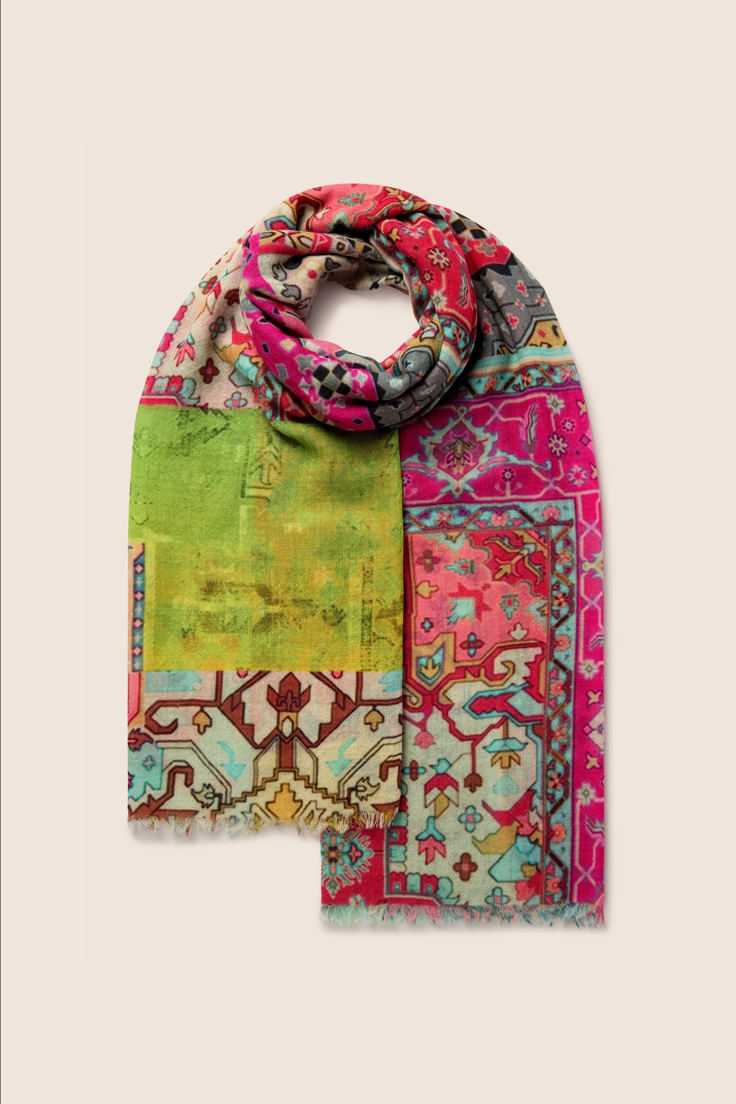 A Medina Wool Scarf featuring a multicolored pattern with geometric and floral designs in shades of green, pink, red, and beige, laid out on a light background for versatile styling.