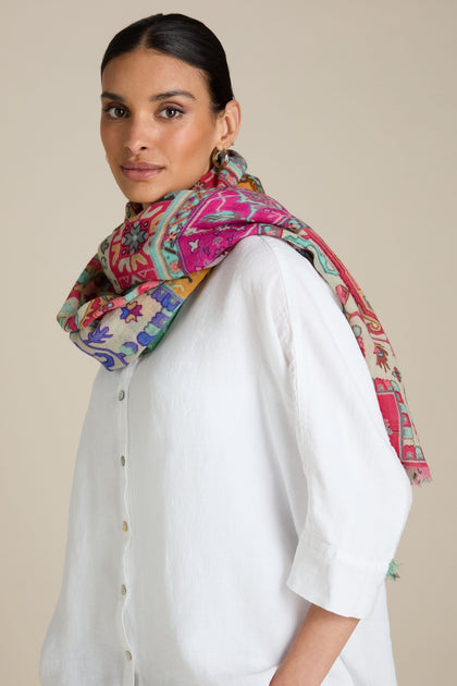 Person wearing a white shirt and a vibrant Medina Wool Scarf inspired by Moroccan motifs, standing against a plain background.