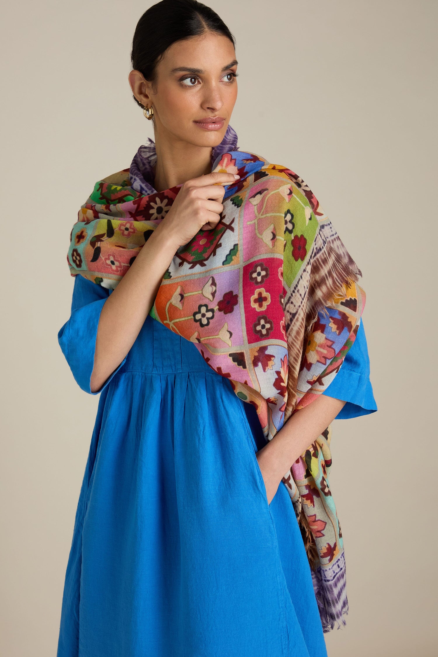 A woman wearing a blue dress and a Patchwork Print Wool Scarf, standing against a beige background.