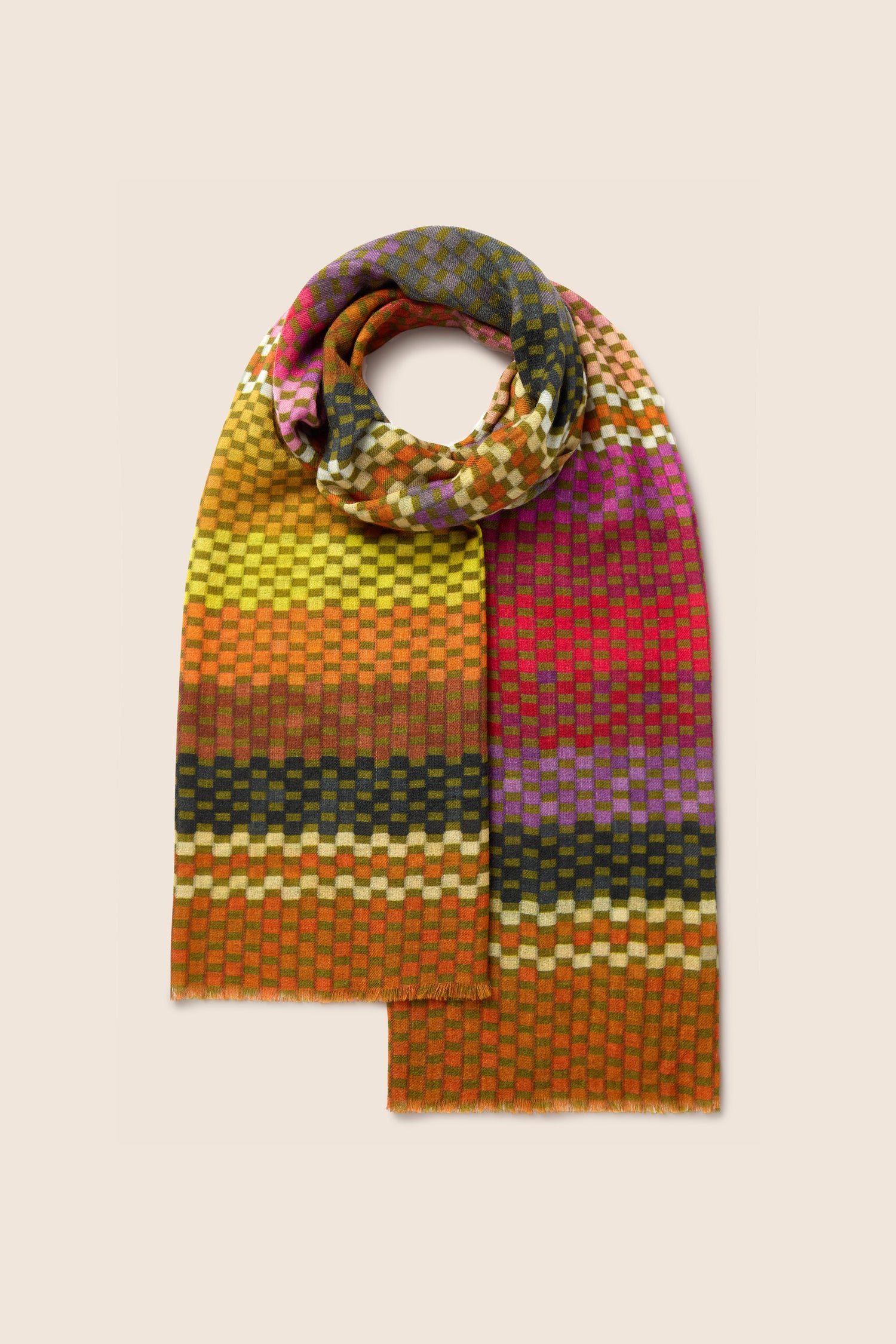 A Mini Squares Wool Scarf, adorned with a multicolored checkerboard pattern featuring gradient shades of orange, red, yellow, green, and purple, is displayed against a beige background.