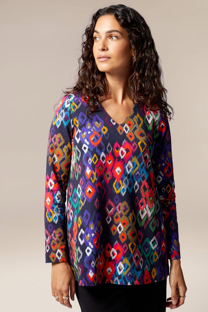 A woman wearing a Tanza Top, a contemporary, multi-colored v-neck top with hints of Nordic style.