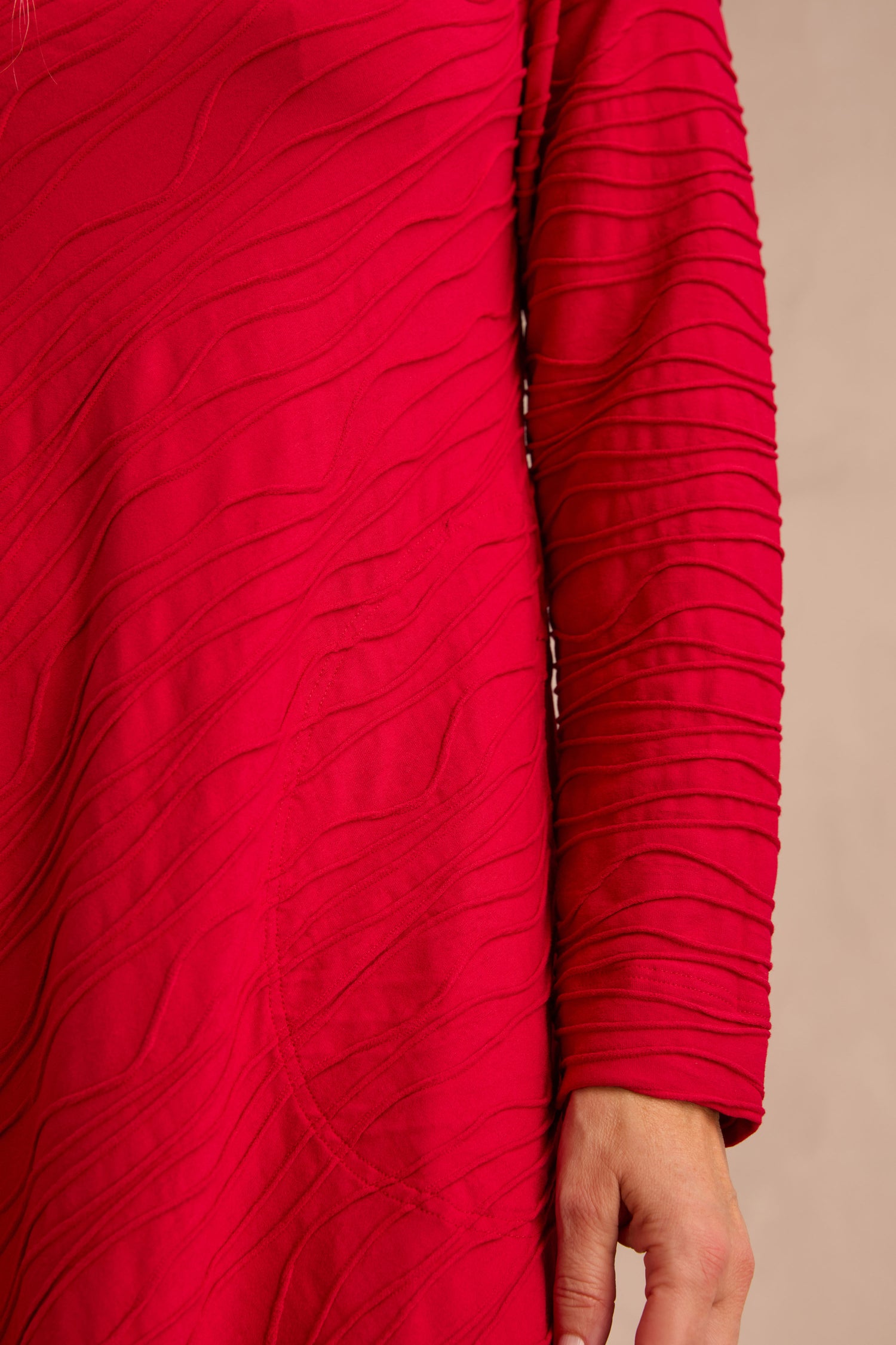 Wearing the Wave Textured Jersey Flared Dress in a vibrant pink, the person’s left arm rests naturally by their side, showcasing the dress’s relaxed fit and eye-catching wavy, raised texture.