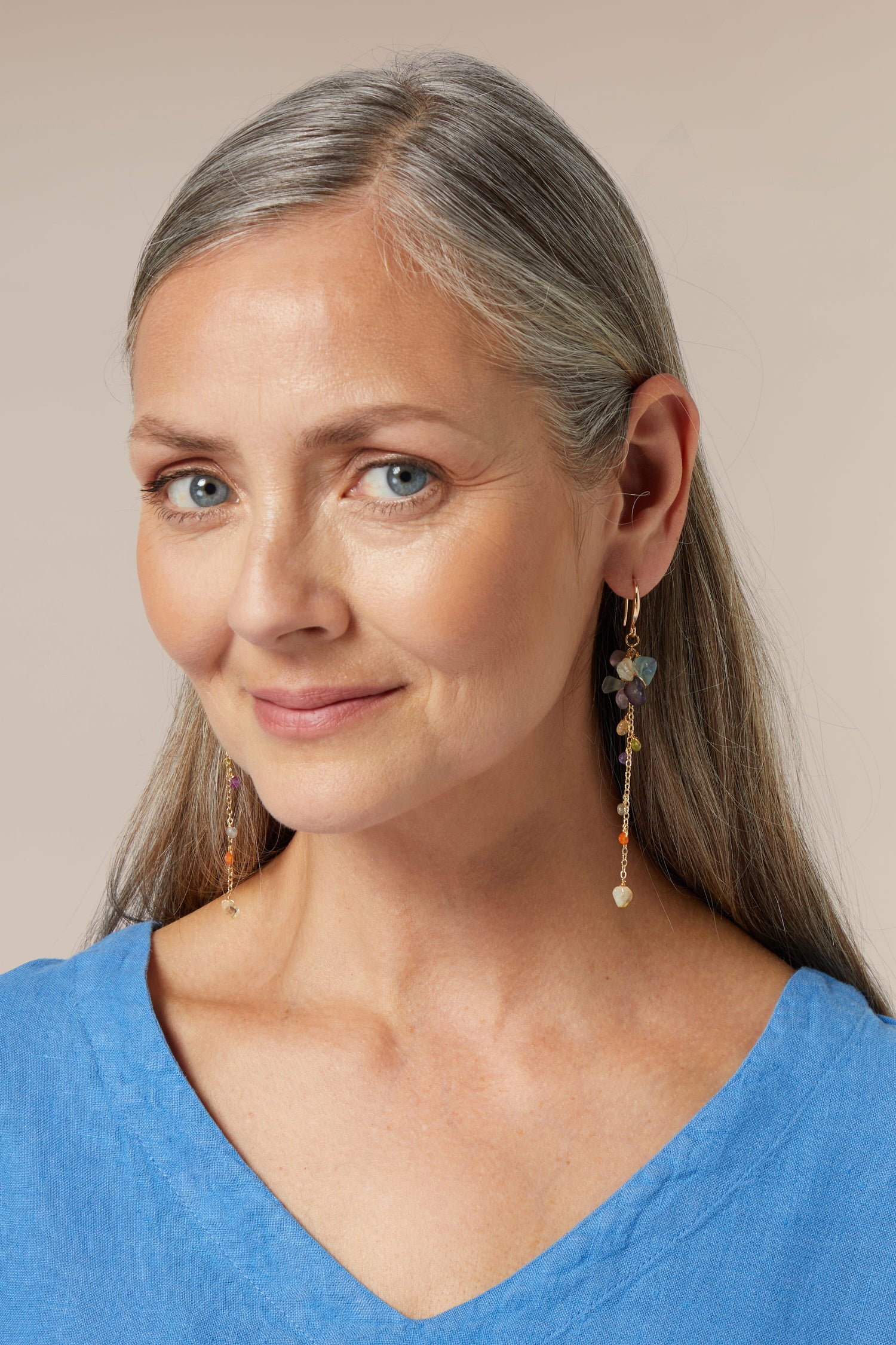 Woman with long gray hair wearing a blue top and gold-plated Rainbow Mini Stones Earrings.