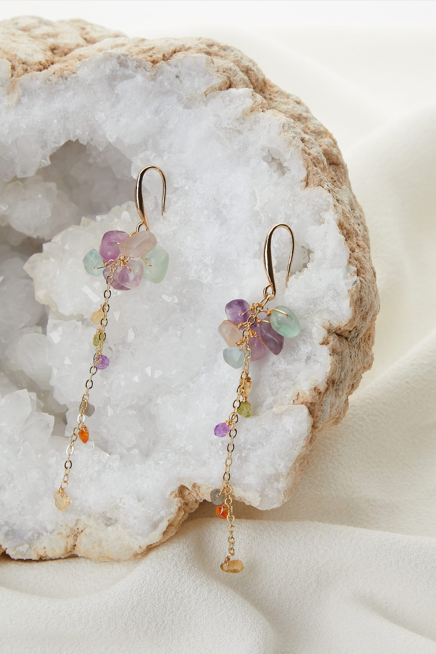 A pair of delicate Mini Stones Earrings displayed on a crystalline white rock.