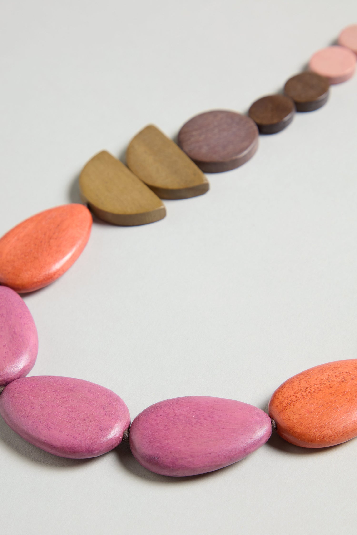 The Assorted Wooden Shapes Necklace features large oval and semicircular beads in pink, orange, purple, brown, and tan—perfect statement jewellery for any occasion.