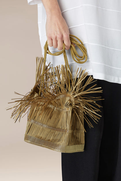 Alexandra Tsoukala is holding a Pleated Handbag with a straw handle.