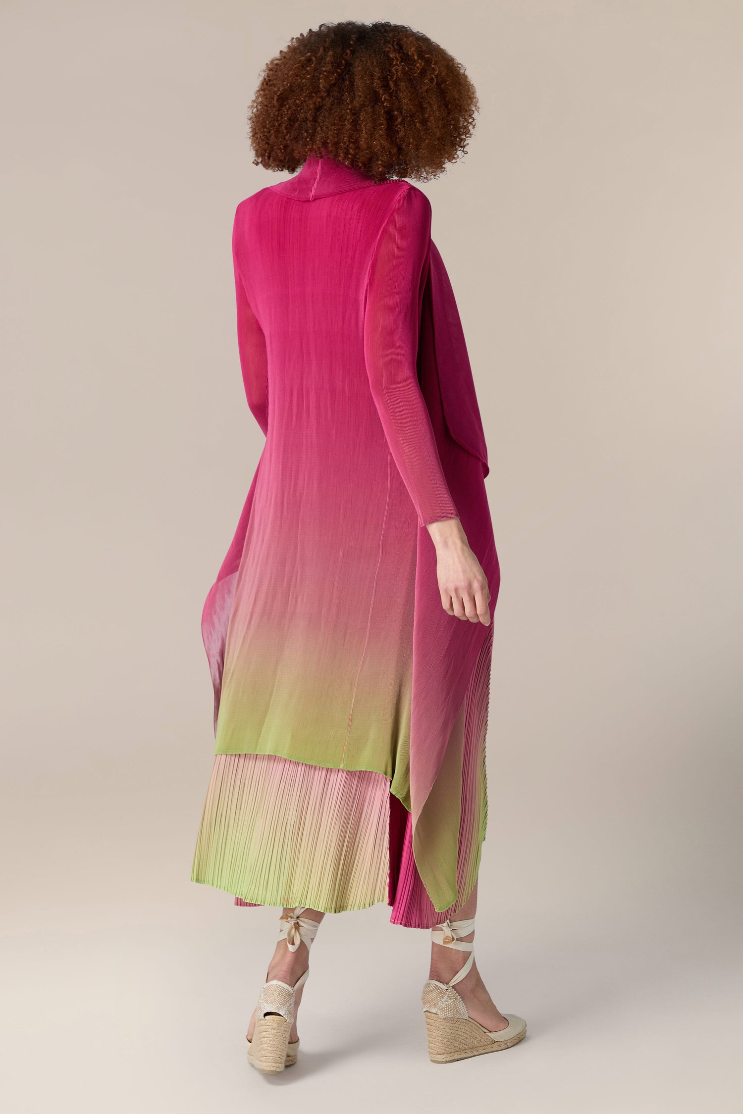 The woman in the pink and green Pleated Jacket is seen from behind.
