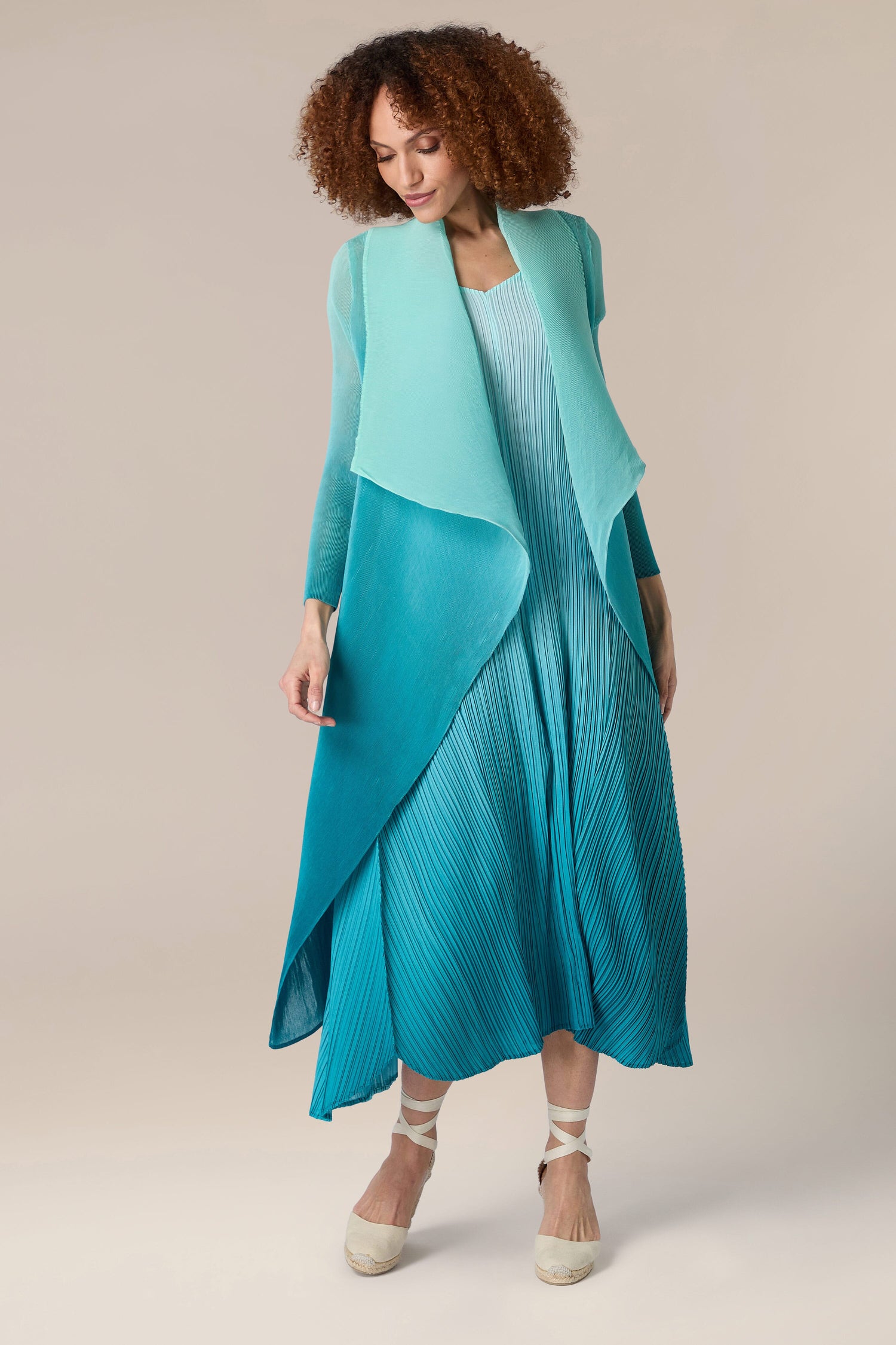 A woman wearing a Pleated Jacket in a blue and teal dress.