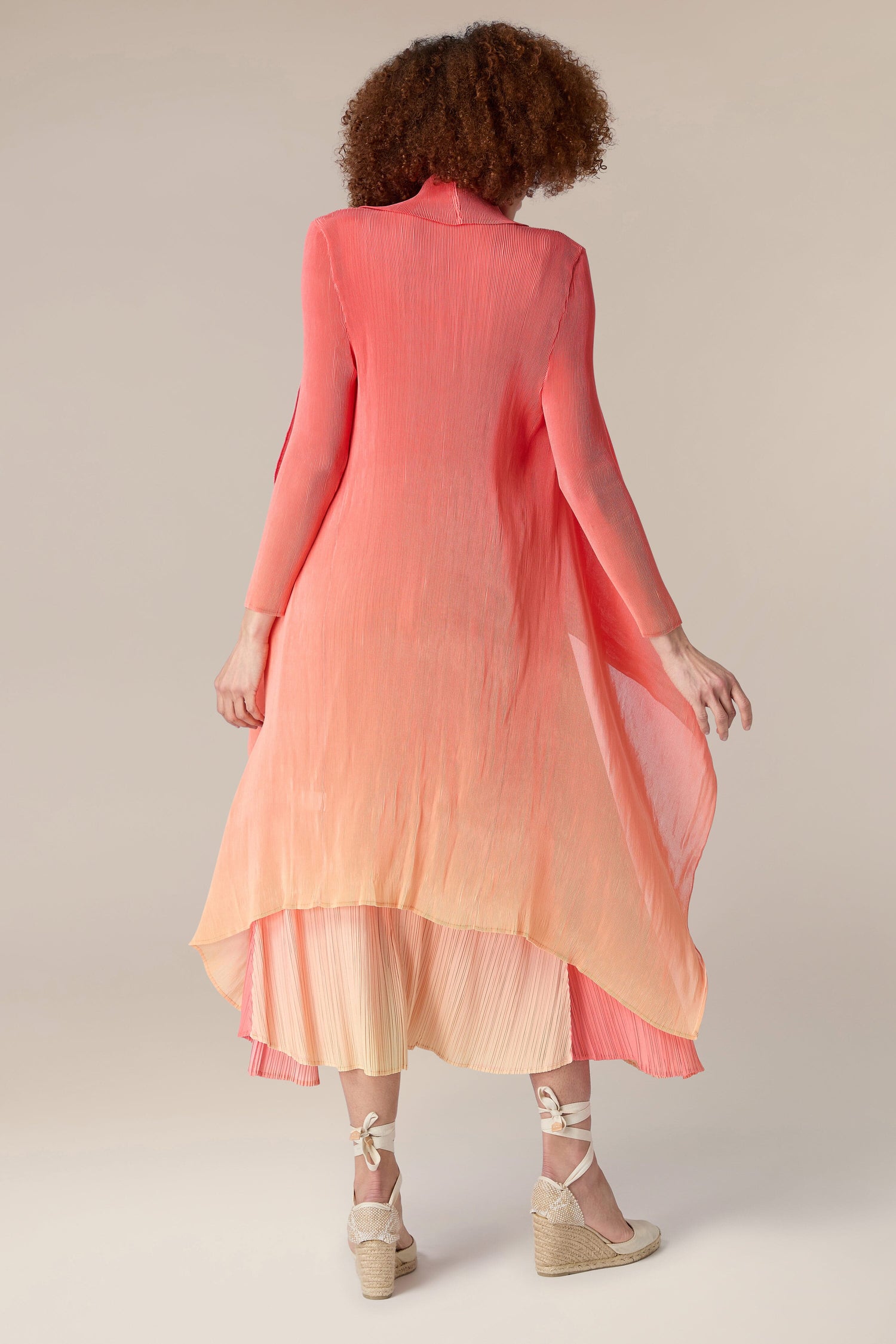The woman in the photo is donning a pink Pleated Jacket, showcasing an ombre design.