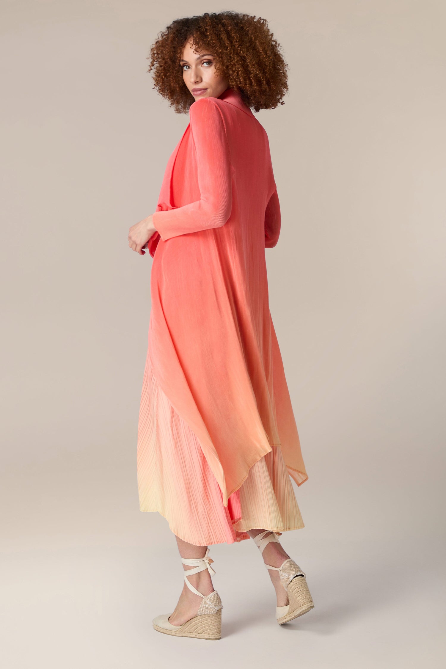 A woman in a Pleated Jacket with a pink and orange ombre design.