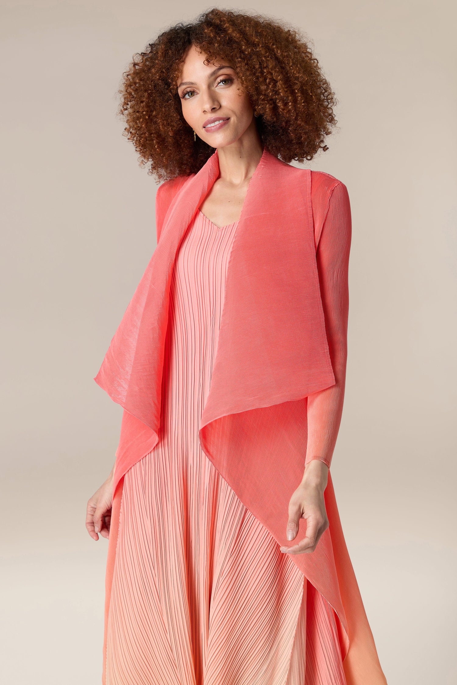 A woman wearing a pink Shibori dress and Pleated Jacket.
