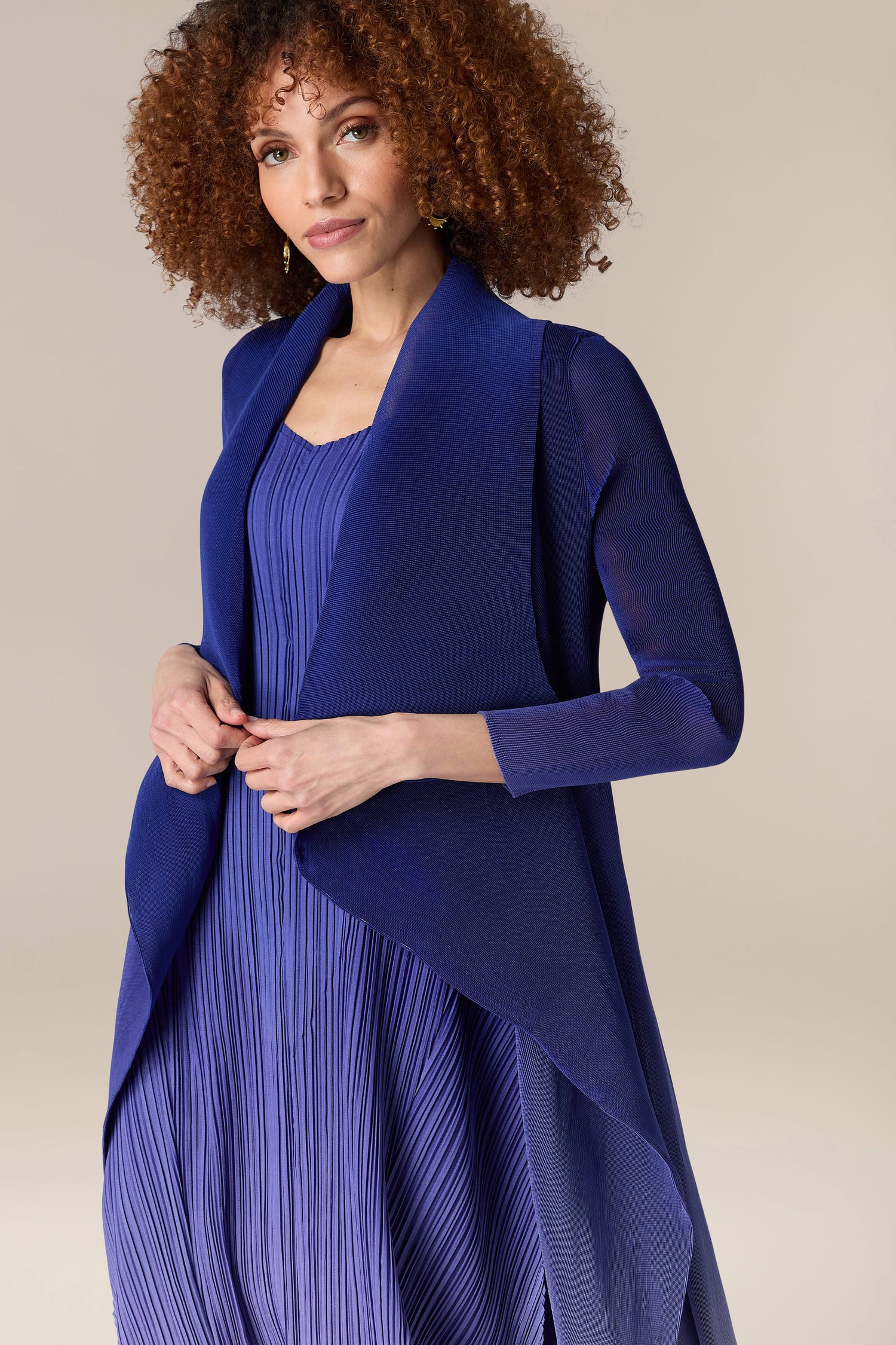 A woman wearing a blue dress and Pleated Jacket.