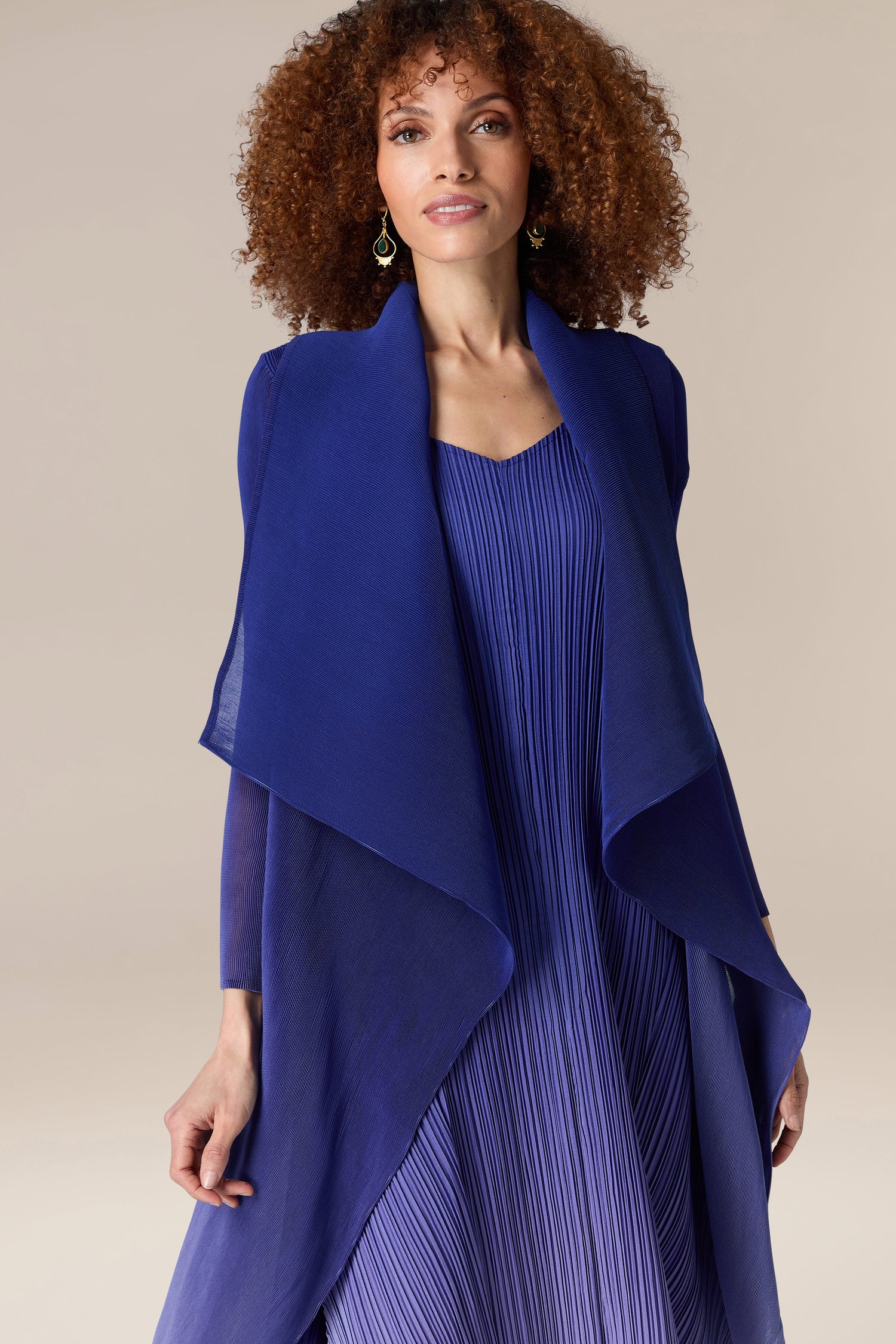A woman wearing a blue dress with a Pleated Jacket by Alquema.