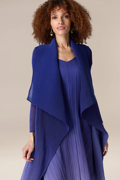 A woman wearing a blue dress with a Pleated Jacket by Alquema.