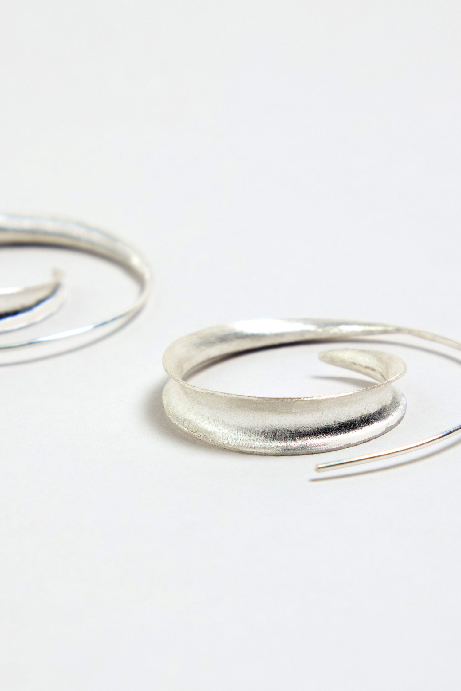 A close-up of the Silver Swirl Earrings, featuring a sterling silver design, displayed on a plain white background.