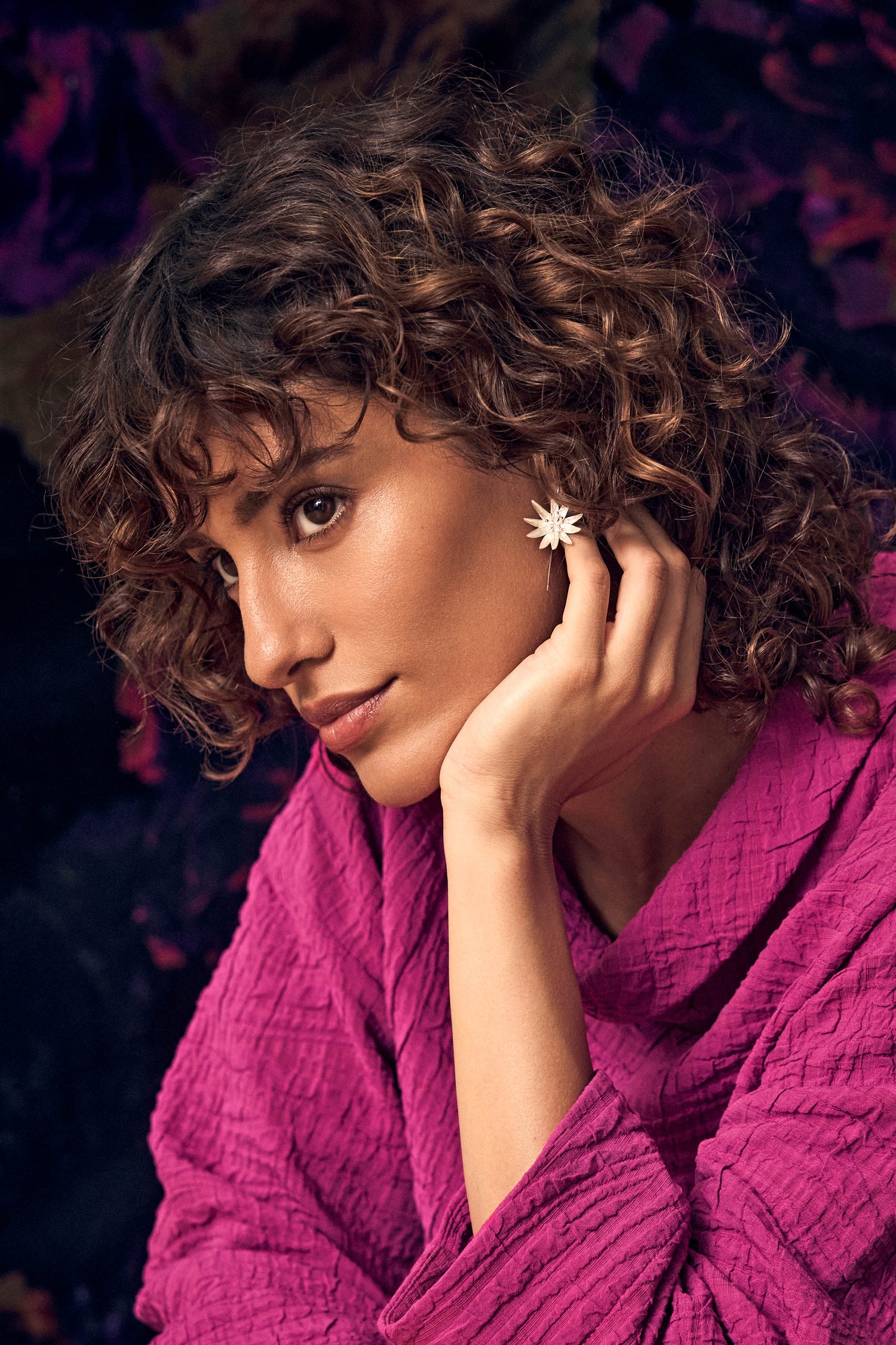 A woman wearing Silver Starflower earrings with a textured, multi-layered star-shaped design.