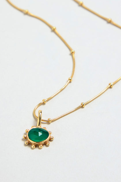 The Gold Vermeil Green Onyx Necklace features a faceted green onyx pendant encircled by small gold beads on a delicate chain, shown against a light background.