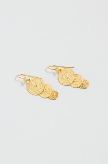 The Gold Vermeil Orbit Disc Earrings feature three textured concentric circle discs of different sizes on each earring, shown against a light background.