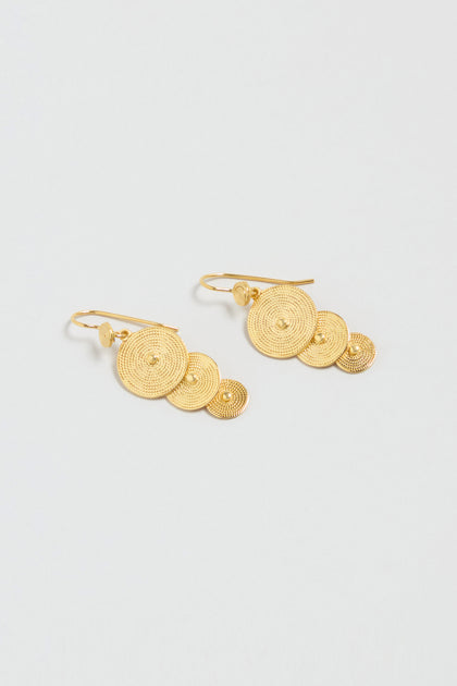 The Gold Vermeil Orbit Disc Earrings feature three textured concentric circle discs of different sizes on each earring, shown against a light background.