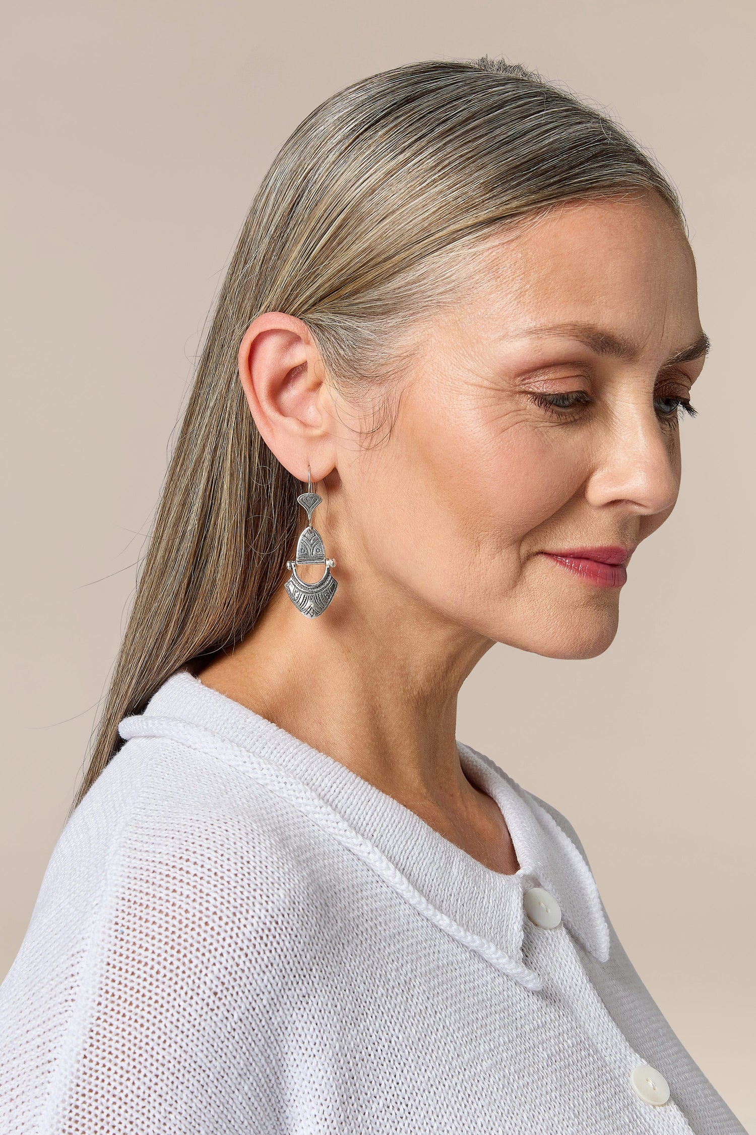 A woman wearing a white shirt and Engraved Silver Tuareg Earrings.