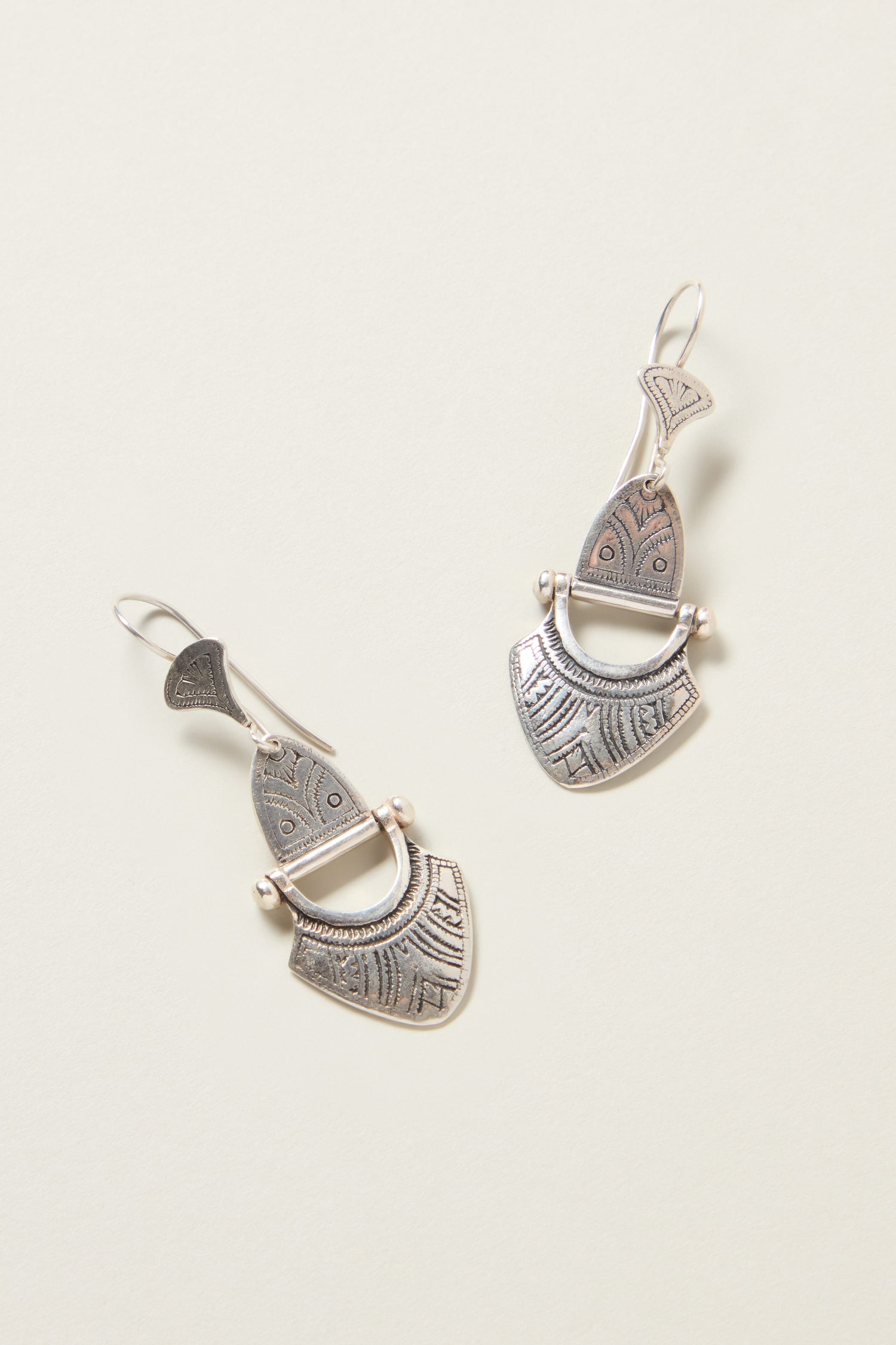 The Engraved Silver Tuareg Earrings, featuring intricately designed, silver-toned drop elements with geometric patterns on a light background, make a stunning addition to any jewelry collection.