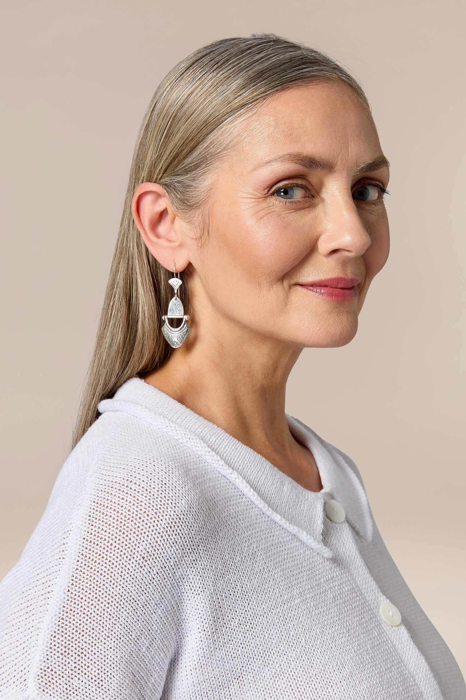 A woman wearing Engraved Silver Tuareg earrings and a white shirt.