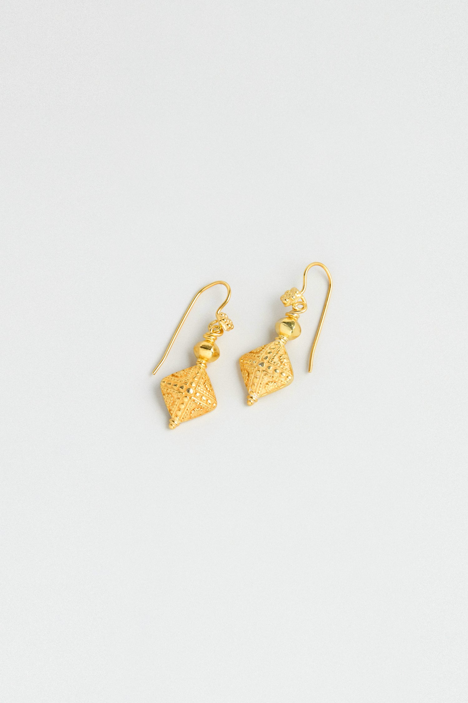 Gold Vermeil Faceted Drop Earrings—lightweight geometric diamond-shaped pendants with bead accents—are showcased on a simple, light background.