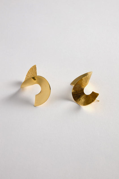 The Gold Vermeil Twist Earrings, featuring two abstract, disc-shaped designs in radiant 18k gold vermeil, grace a white background.