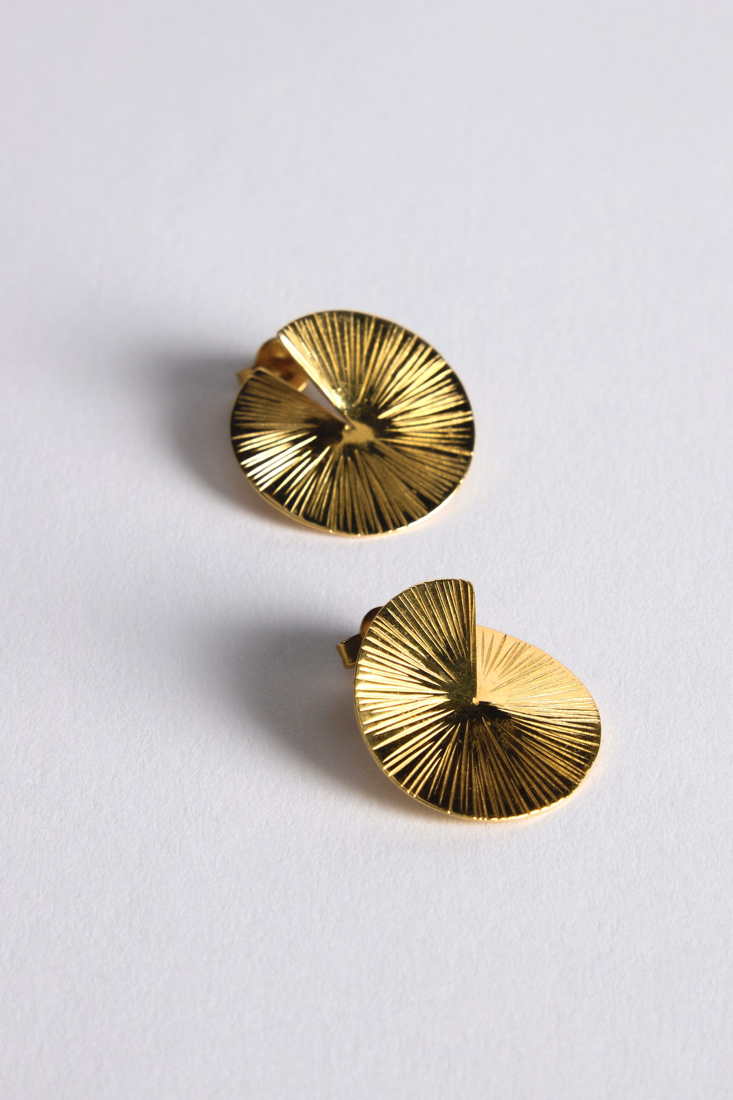 The Small Gold Vermeil Lotus Leaf Earrings are two circular gold pieces with a textured sunburst pattern, displayed on a plain white background.