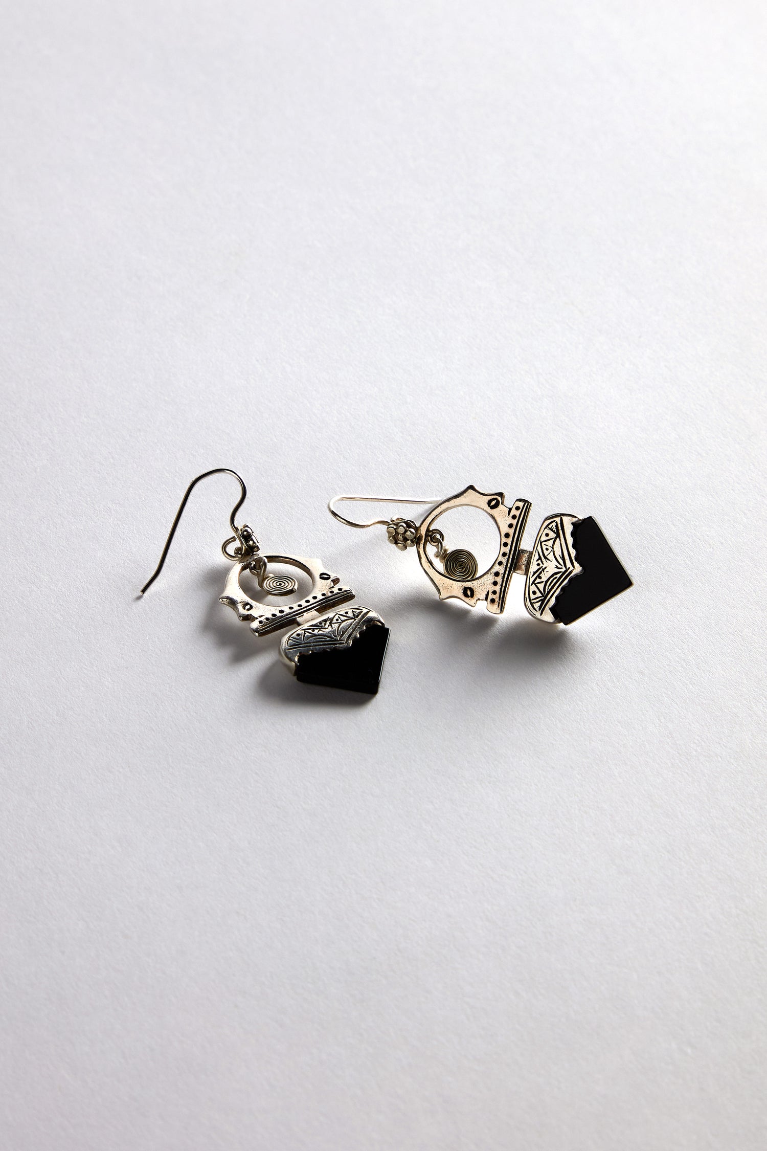 The Silver and Black Onyx Tuareg Earrings, made of sterling silver with black onyx stone accents, were elegantly displayed on a white surface.