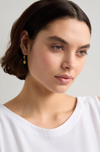 A woman with short brown hair wears a white top and elegant Gold Vermeil Lapis Bead Earrings, looking to the side.