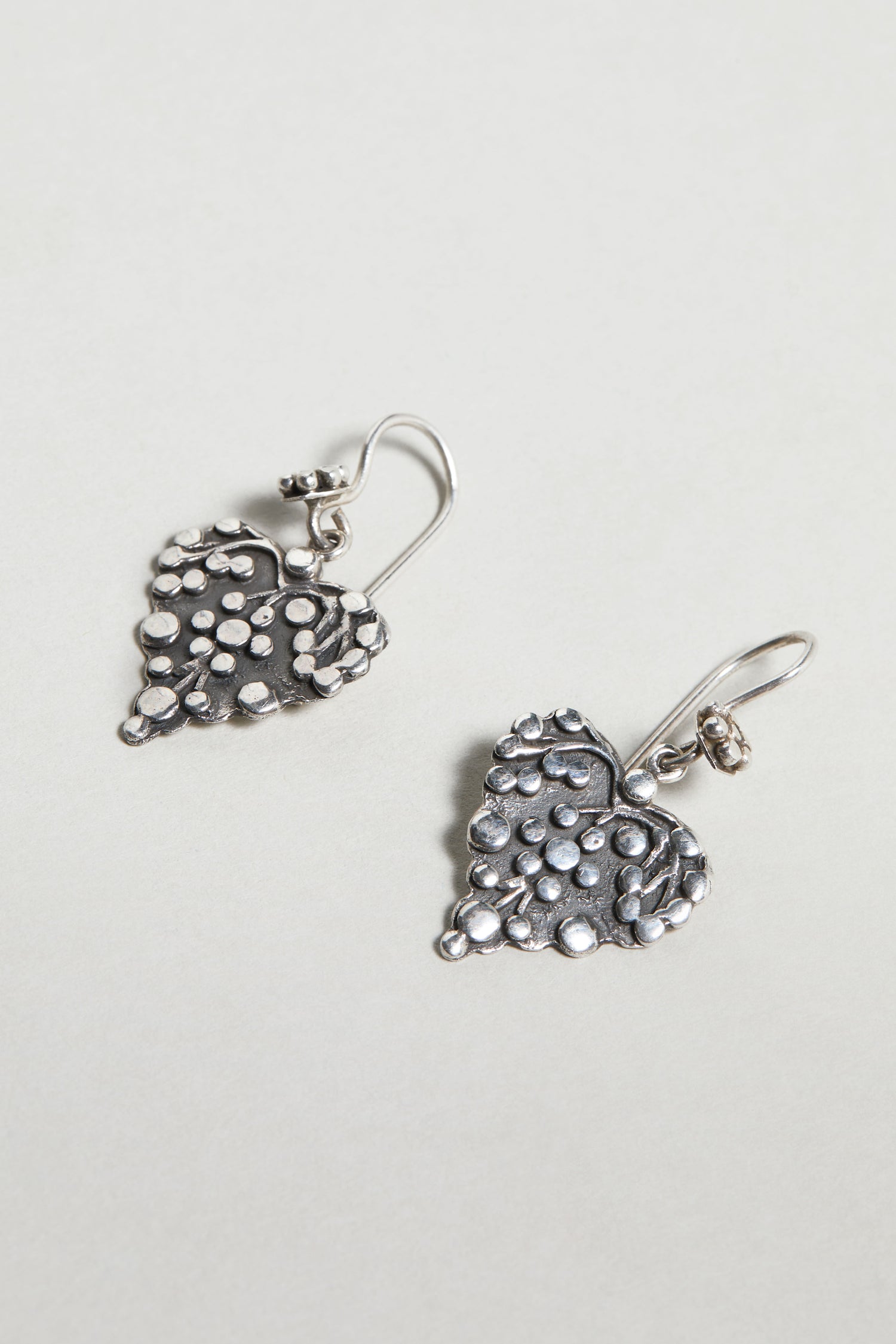 Silver Heart Earrings with a textured, dotted surface and hook fastenings are displayed on a light background.
