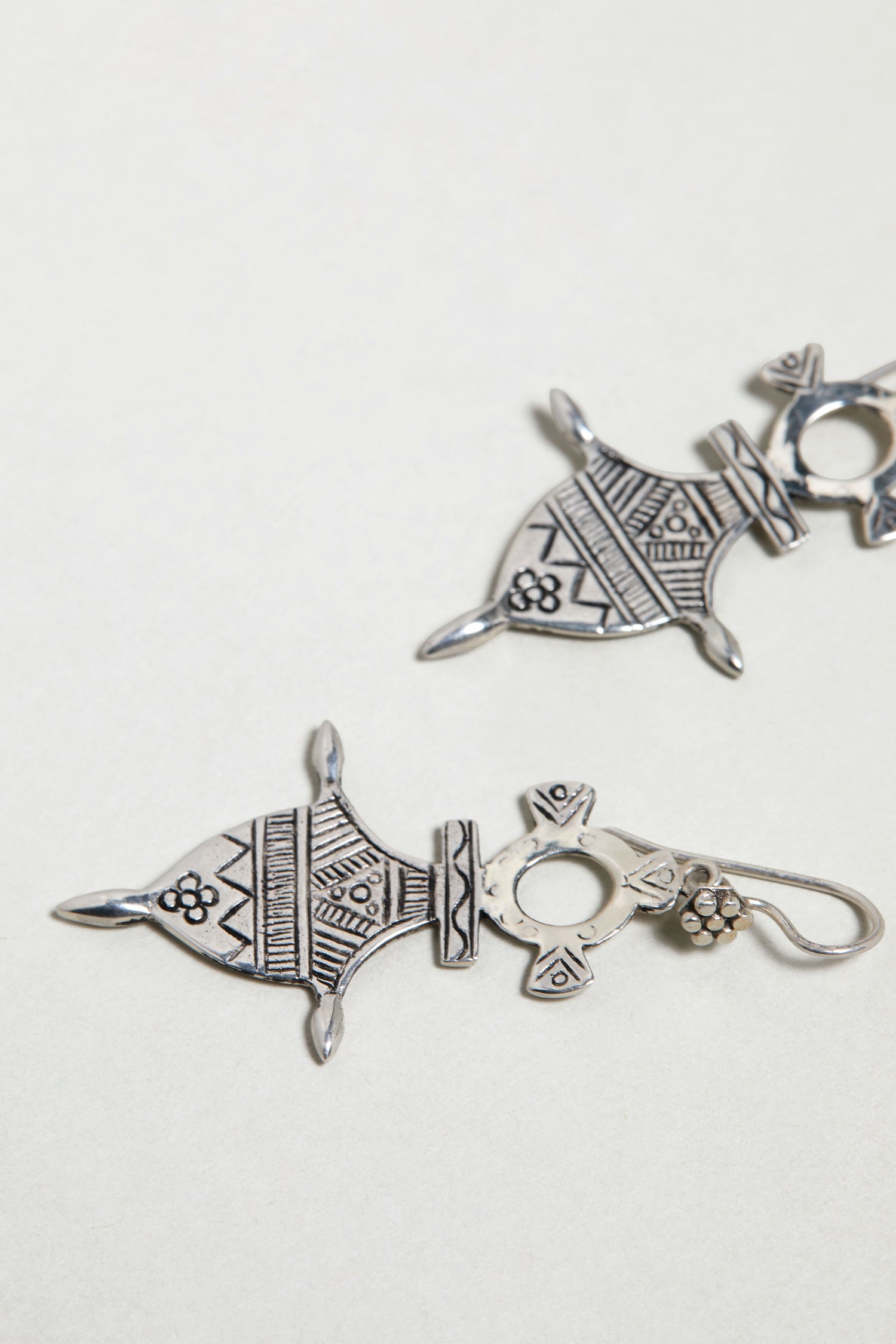 Close-up of Silver Tuareg Earrings with geometric engraving and floral patterns, crafted in sterling silver and inspired by traditional Tuareg designs, displayed on a plain white background.