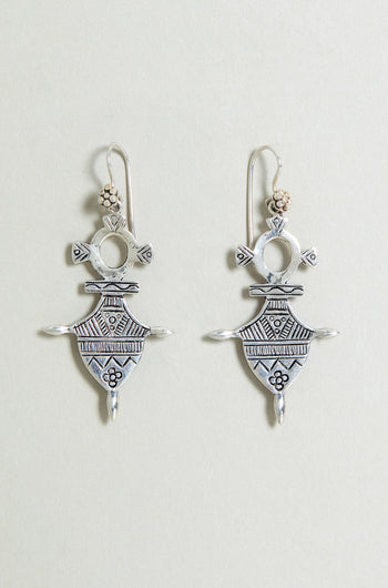 The Silver Tuareg Earrings feature sterling silver with detailed geometric and floral engravings on a light background, inspired by classic Tuareg designs.