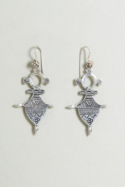 The Silver Tuareg Earrings feature sterling silver with detailed geometric and floral engravings on a light background, inspired by classic Tuareg designs.
