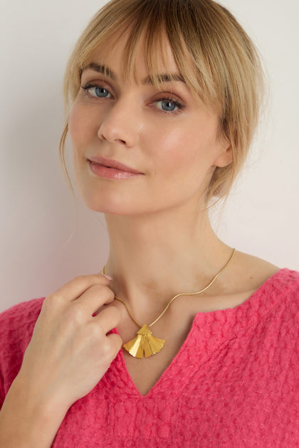 A woman in a textured pink top wears the Gold Vermeil Ginkgo Leaf Pendant necklace and looks at the camera against a plain background.
