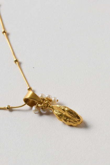 The Gold Vermeil Pearl Drop Necklace features a textured gold leaf pendant and small freshwater pearls, creating an elegant accessory that stands out beautifully against light backgrounds.