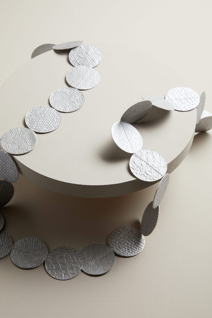 A white plate with silver circles on it became the Dotty Necklace.