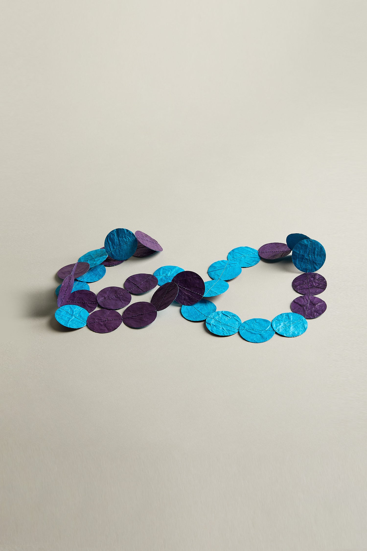 An arrangement of Dotty Necklace's purple and blue circular paper beads, positioned on a neutral background, forming the number "2020.