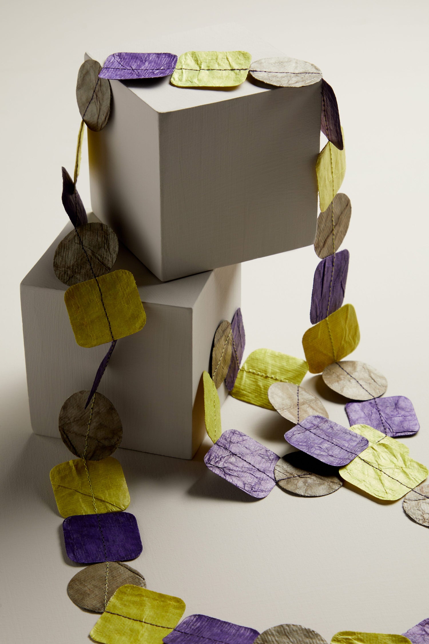 A purple and yellow paper garland adorned with Dotty Necklace.