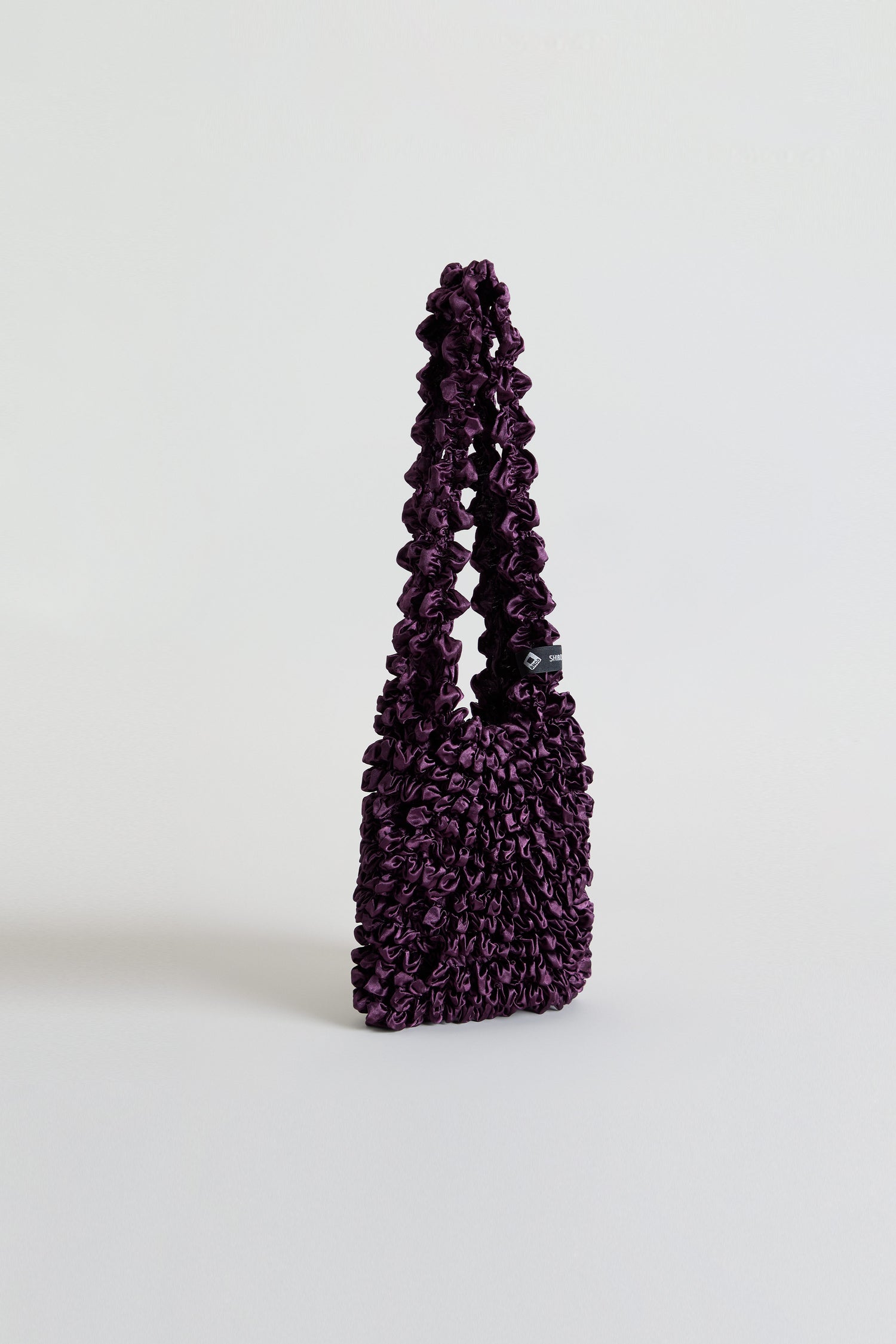 Aubergine Shibori Pleated Bag in deep purple with a gathered texture and a single loop handle.