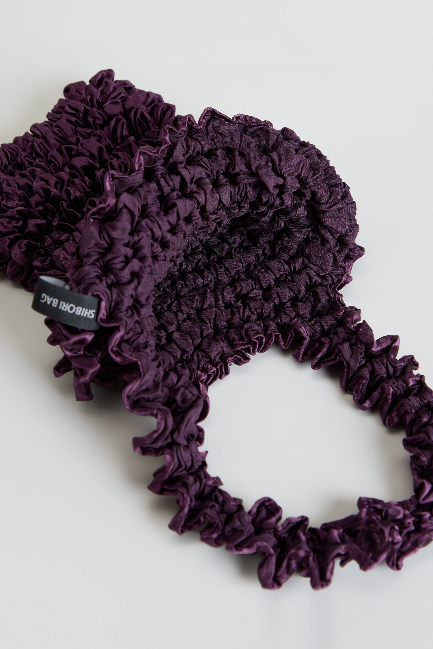 Aubergine Shibori Pleated Bag in deep purple with a gathered, puckered texture and a matching ruched circular handle.