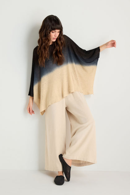 Model wearing the Dip Dye Knit Easy Top with wide-legged beige pants, standing against a plain white wall.