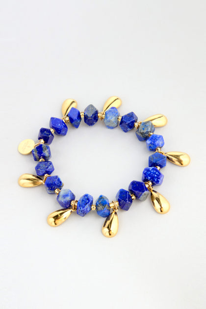 The Lapis Lazuli Teardrop Bracelet features blue stone beads and gold teardrop-shaped charms, beautifully arranged in a circle on a light background.