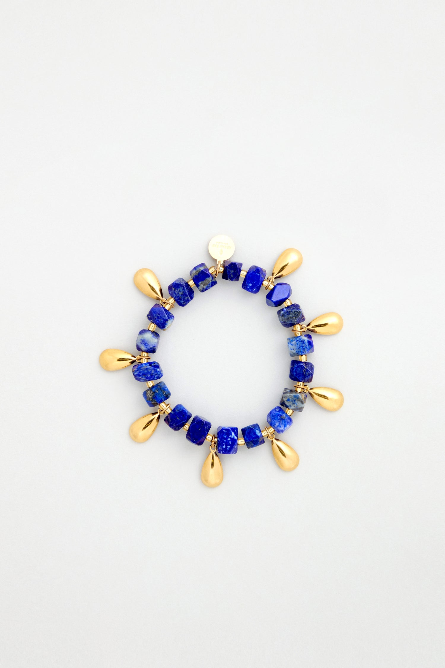 The Lapis Lazuli Teardrop Bracelet features square blue lapis lazuli beads and gold charms, handmade in Scotland, shown on a plain white background.
