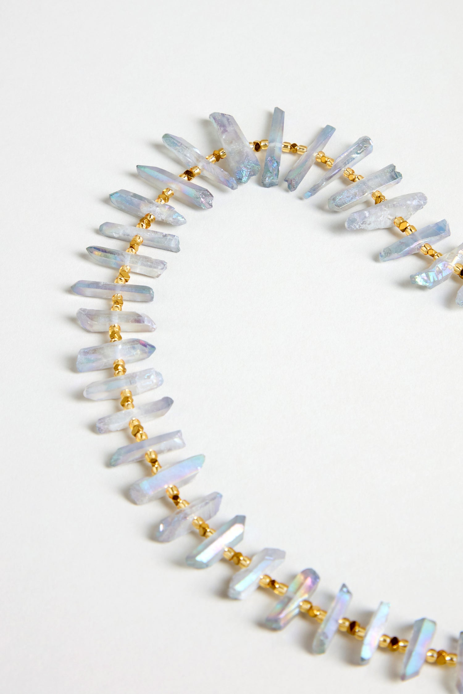 The Slate Quartz Necklace, a gold-plated statement piece featuring irregular translucent crystal shards, is displayed on a white background.